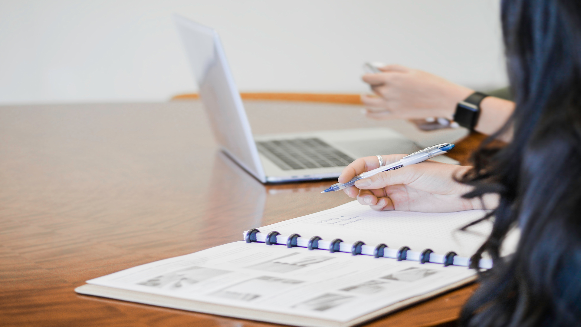 two people meeting with a binder of paperwork and computer