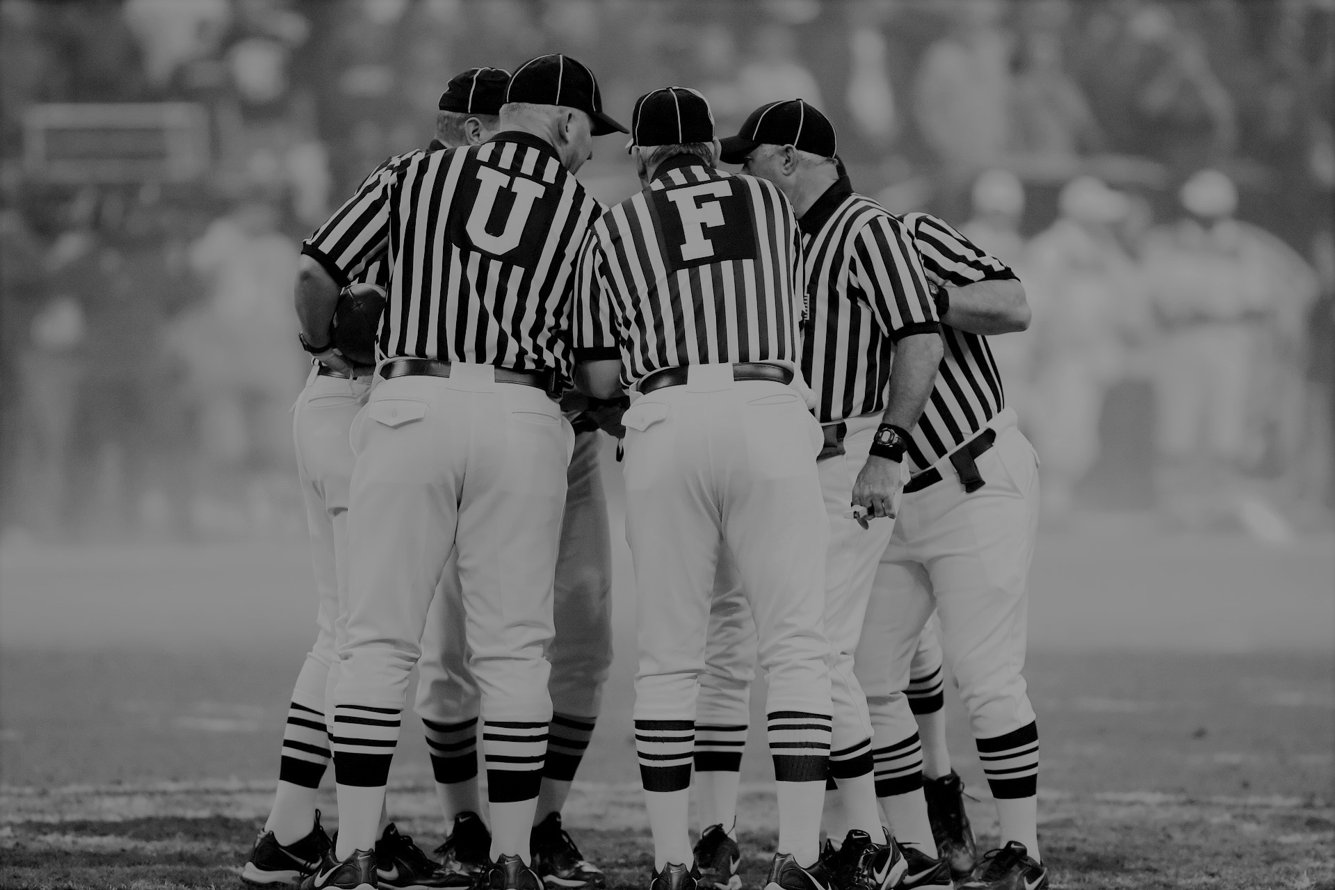 black and white image of football refs huddled together